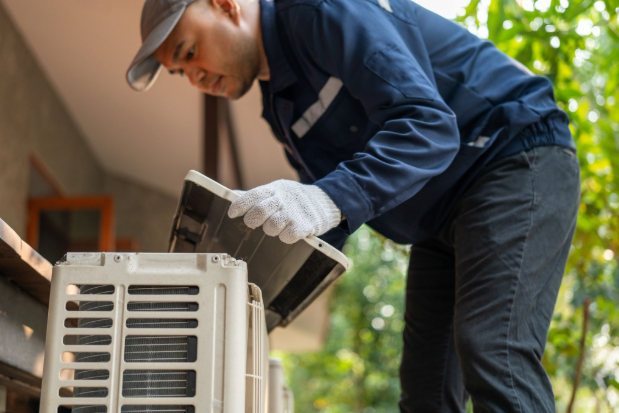 An HVAC technician fixing an outdoor unit